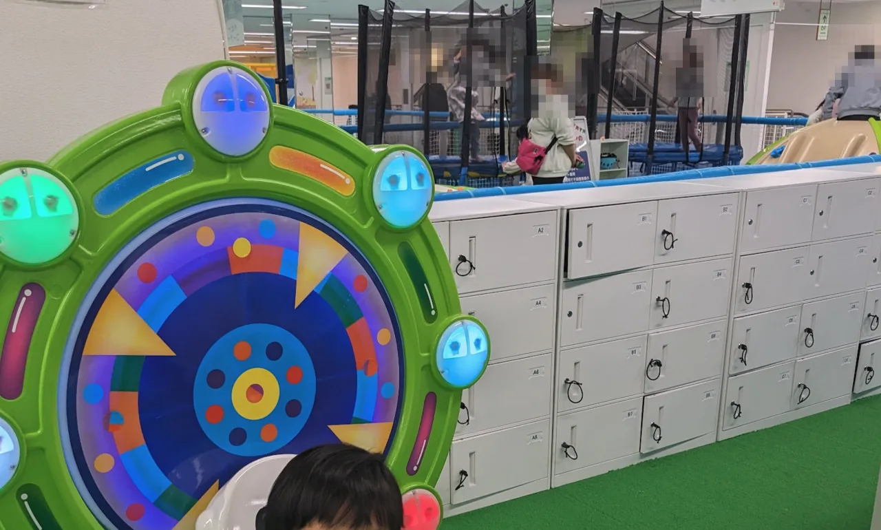 大型のルーレット型遊具と、ずらりと並んだロッカー。奥にはトランポリンエリア