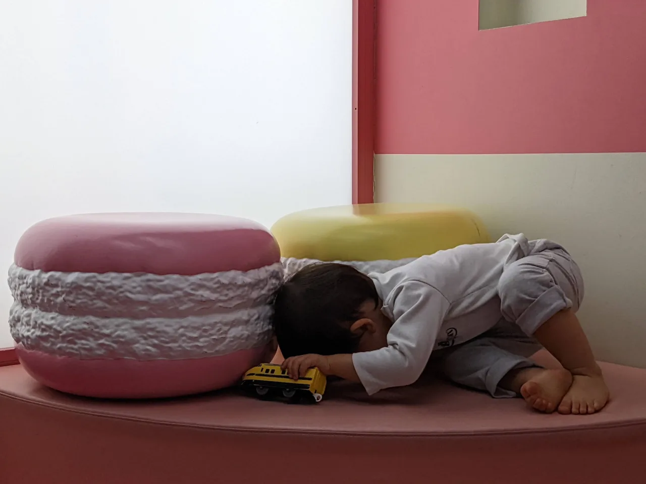 巨大なマカロンのクッションが置かれたコーナーで、子どもがミニカーを走らせている
