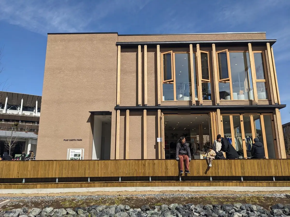 明治公園の木を多用した二階建ての建物。ガラス張りで、テラス側に人が座っている